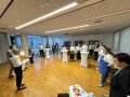 Personen stehen in einem großen Halbkreis in einem Veranstaltungssaal