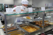 Schülerin in Großküche bei der Essensausgabe.